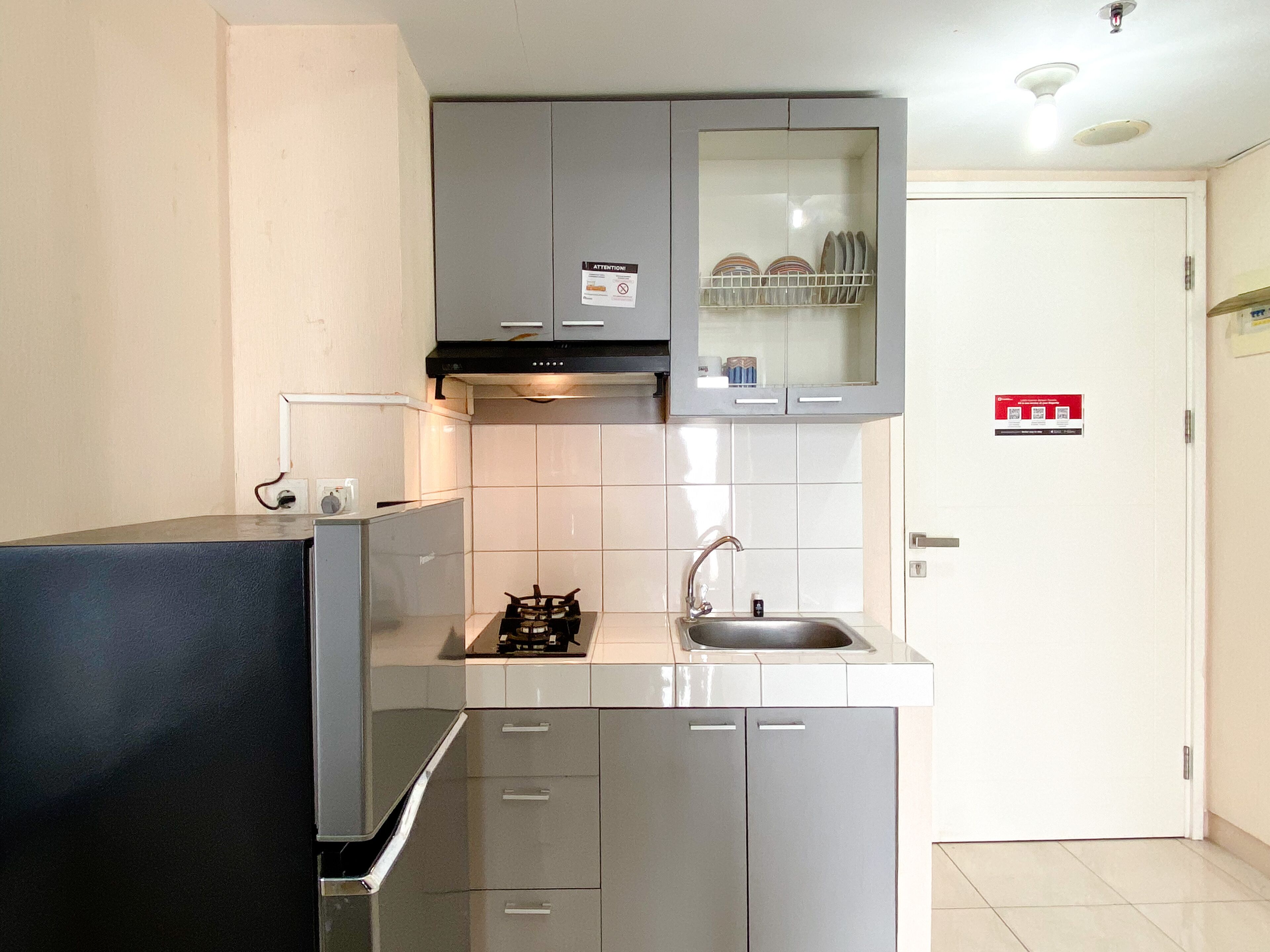 A compact kitchen with grey cabinets, a stainless steel sink, and a gas stove.