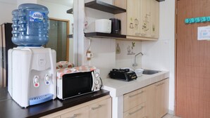 Een keuken met een waterdispenser, magnetron, broodrooster en een grote waterkan.