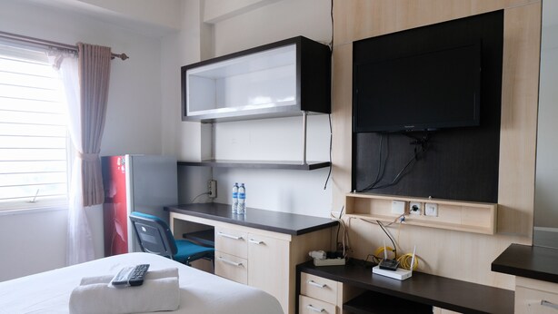 Een hotelkamer met een bed, een bureau met computer, een televisie en een stoel.