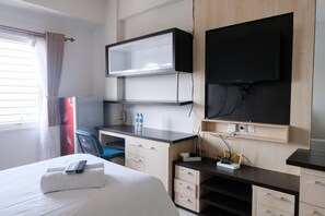 A hotel room with a bed, a desk with a computer, a TV, and a chair.