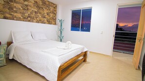 A bedroom with a bed, a stone wall, a window, and a door leading to a balcony. - Casa Playa James  (Cartagena)