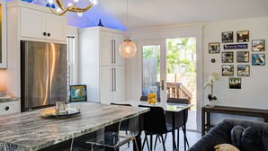 Una cocina moderna con un refrigerador de acero inoxidable, una encimera de mármol y un comedor con mesa y sillas.