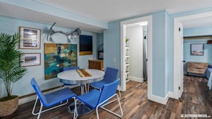 A dining area with a round table and blue chairs, a large abstract painting, and a plant. - #1 Pendleton Cottage / Midtown Hideaway / & More (Anchorage)