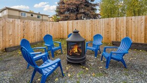 A patio area with a wood-burning stove surrounded by blue plastic chairs.