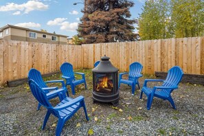A patio area with a wood-burning stove surrounded by blue plastic chairs. - #5 - Walkable cottage near restaurants and trails. (Anchorage)