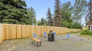 A gravel patio with a wooden fence, a bench, and three blue chairs. - Walking distance to restaurants, trails, and cafes.  10 min. uber from airport. (Anchorage)