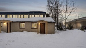 A snow-covered building with numbered doors and windows, surrounded by snow. - 1964 Earthquake Cottage At Slumber Village (Anchorage)
