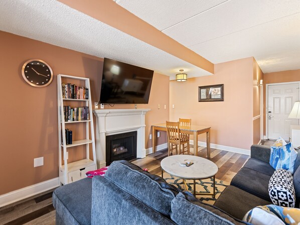 Una sala de estar con chimenea, televisión, estantería y sofá.