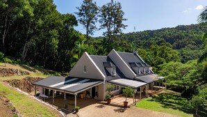 Une maison dotée d’un patio couvert, d’un garage et offrant une vue sur une forêt verdoyante et luxuriante.