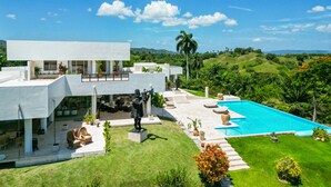 Une maison moderne dotée d’une piscine, d’un espace salon extérieur et d’une statue.