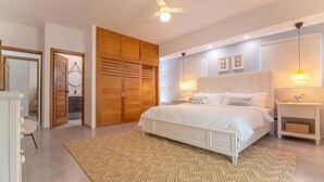 A bedroom with a large bed, wooden wardrobe, and a ceiling fan. - 3BR Renovated Beachfront Condo + Cooking/Cleaning (Las Terrenas)