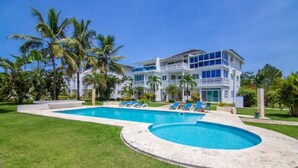 A large, two-story building with a swimming pool and palm trees. - 3BR Renovated Beachfront Condo + Cooking/Cleaning (Las Terrenas)