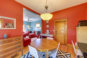 A dining area with a wooden table, white chairs, and a hanging light fixture.