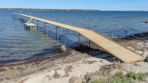Puinen laituri, joka ulottuu vesistöön, ja sen päässä seisoo henkilö.