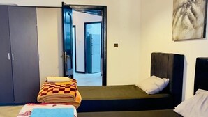 Un dormitorio con cama, armario, un cuadro y una puerta que da a otra habitación.