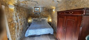 Une petite pièce avec un lit, une armoire en bois et une petite fenêtre.