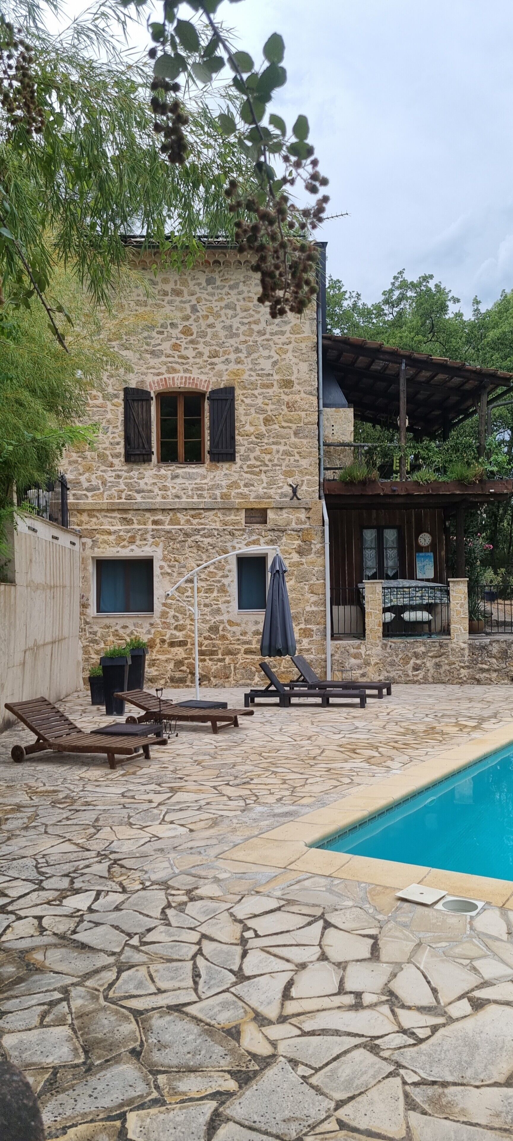 Un bâtiment en pierre doté d’une piscine, d’un espace extérieur aménagé et d’une zone couverte.