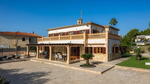 A two-story building with a balcony, outdoor seating, and a small garden. - Villa Can Tosam Meiga with Wi-Fi, Pool, Terraces & Balcony (Cales de Mallorca)