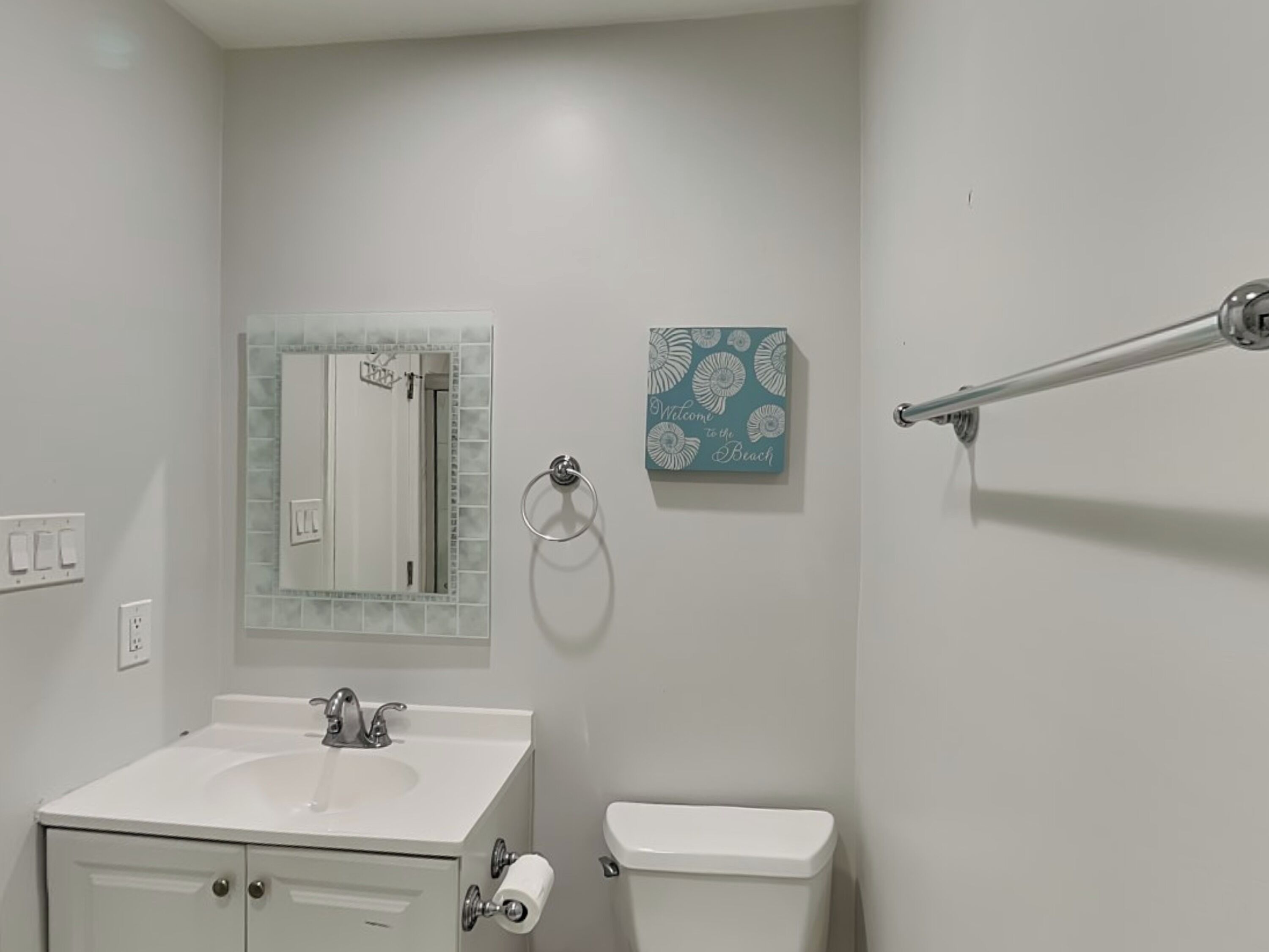 Une salle de bain avec un lavabo blanc, des toilettes, un miroir et un porte-serviettes.