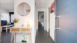 A modern interior with a round mirror, a console table with plants, a sofa, and a hallway leading to another room. - Vacation Home 'The Garden Secret' with Shared Pool, Private Terrace and Wi-Fi (Villaverde)