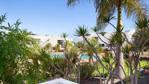 A pool surrounded by palm trees and a white building. - Vacation Home 'The Garden Secret' with Shared Pool, Private Terrace and Wi-Fi (Villaverde)