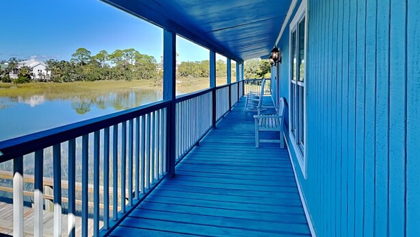 A blue wooden porch with white railings, overlooking a calm body of water and trees. - Saltcreek Sunsets by Tybee Vacation Rentals (Tybee Island)
