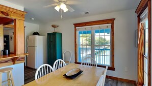 A kitchen with a dining table, chairs, a ceiling fan, and a window with a view. - Saltcreek Sunsets by Tybee Vacation Rentals (Tybee Island)