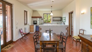 A spacious kitchen with a central island, a dining area with a wooden table and chairs, and a chandelier. - Holiday Home "Casa Flora" with Private Pool, Private Terrace and Wi-Fi (Monteverdi Marittimo)