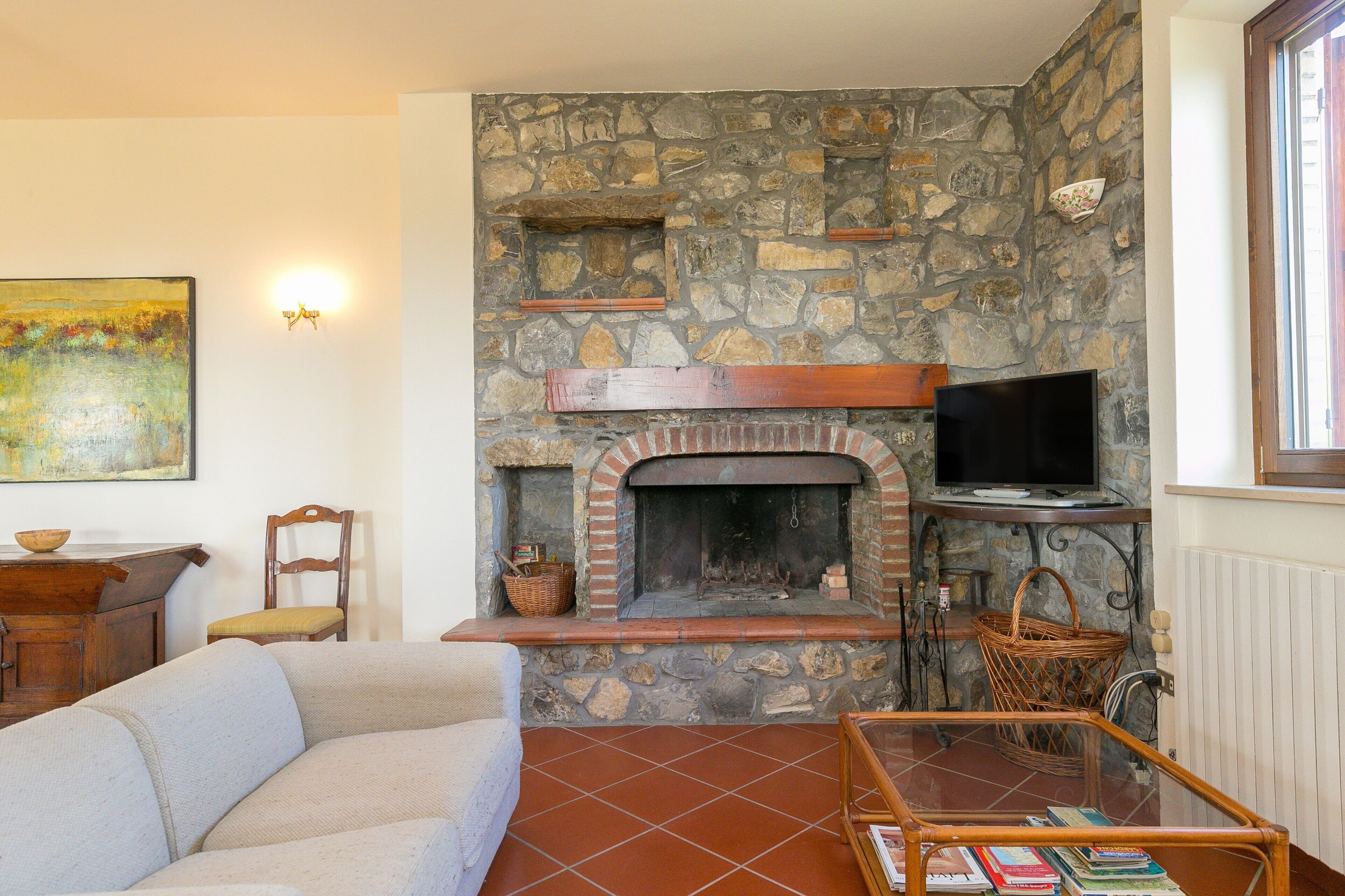 A living room with a stone fireplace, a television, a sofa, and a coffee table.