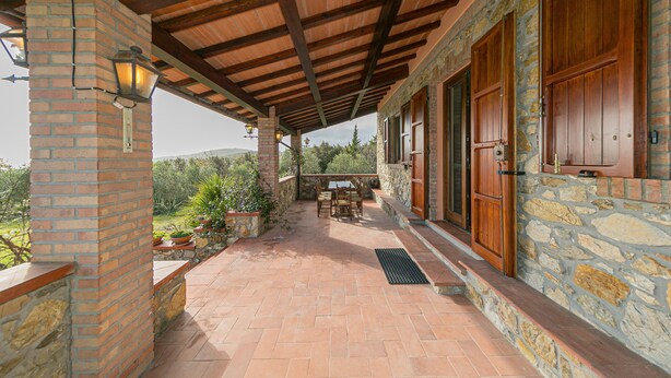 A covered patio with a brick wall, wooden door, and a table with chairs. - Holiday Home "Casa Flora" with Private Pool, Private Terrace and Wi-Fi (Monteverdi Marittimo)