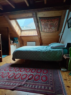 Una camera da letto con un letto, un tappeto decorato, una finestra e un soffitto in legno.