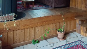 Een gezellige kamer onder de schuine kap met houten balken, een bank, een kleine tafel, een potplant en een open haard.