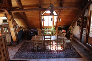 A wooden dining area with a table and chairs, a patterned rug, and a view of the outdoors through a window. - Holiday Home 'Landrosace' with Shared Terrace, Balcony and Wi-Fi (Le Monêtier les Bains)