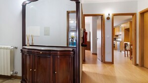 Habitación con un espejo grande, un armario de madera, un radiador y vistas a una zona de cocina.