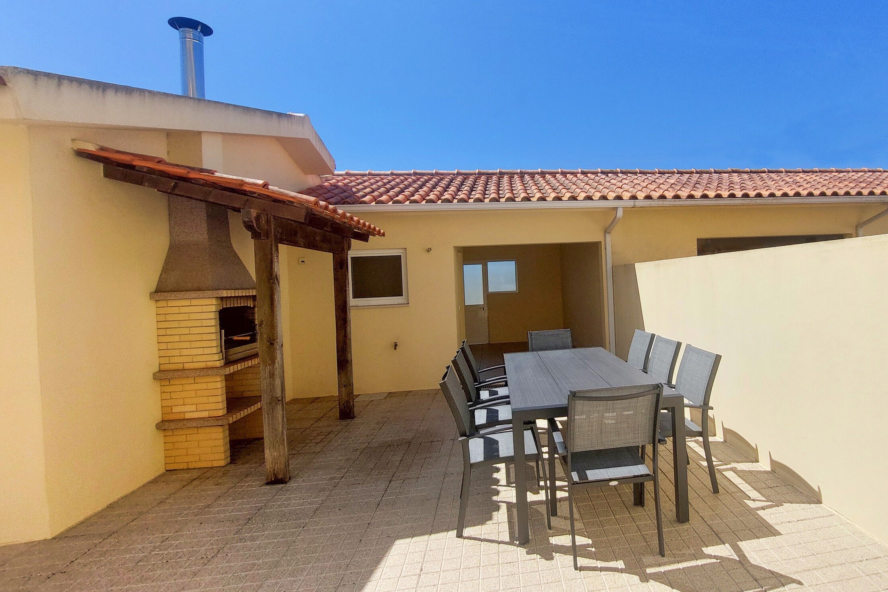An outdoor patio with a brick floor, a grill, and a table with chairs.