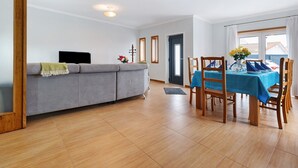 Una sala de estar con sofá, televisor y comedor con mesa y sillas.