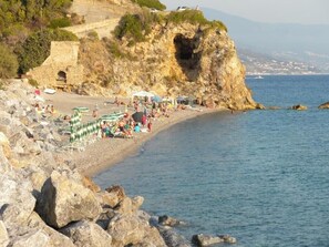 Une plage côtière avec un terrain rocheux, une formation rocheuse en forme de cœur et une vue dégagée sur la mer.