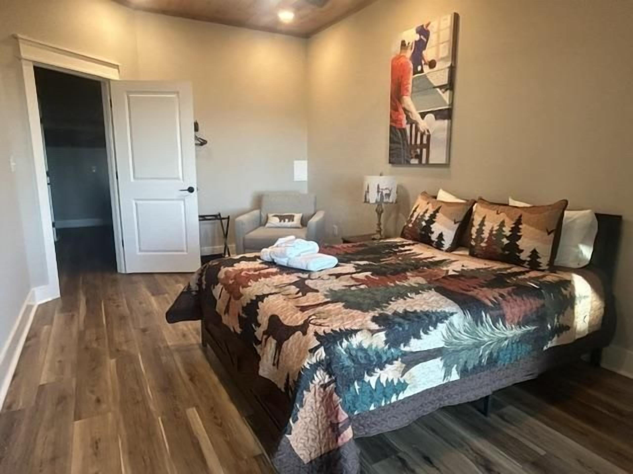 Ein Schlafzimmer mit Bett, Stuhl, Tür und einem Gemälde an der Wand.