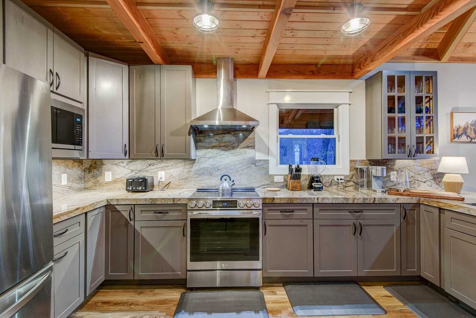 A modern kitchen with stainless steel appliances, a large stove, and a window with a view.