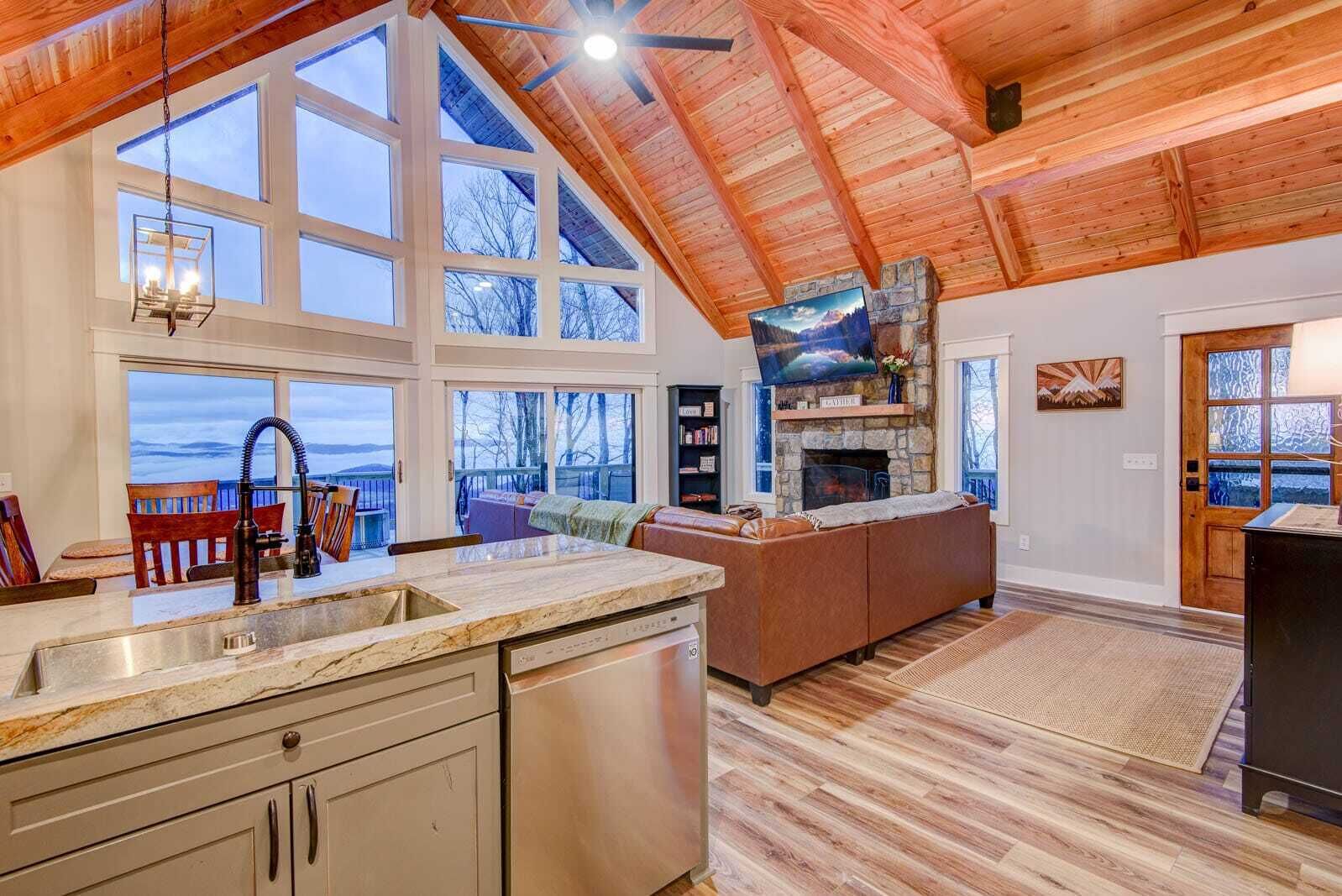 A spacious kitchen with a large window, a stone fireplace, and a cozy seating area with a view of the outdoors.