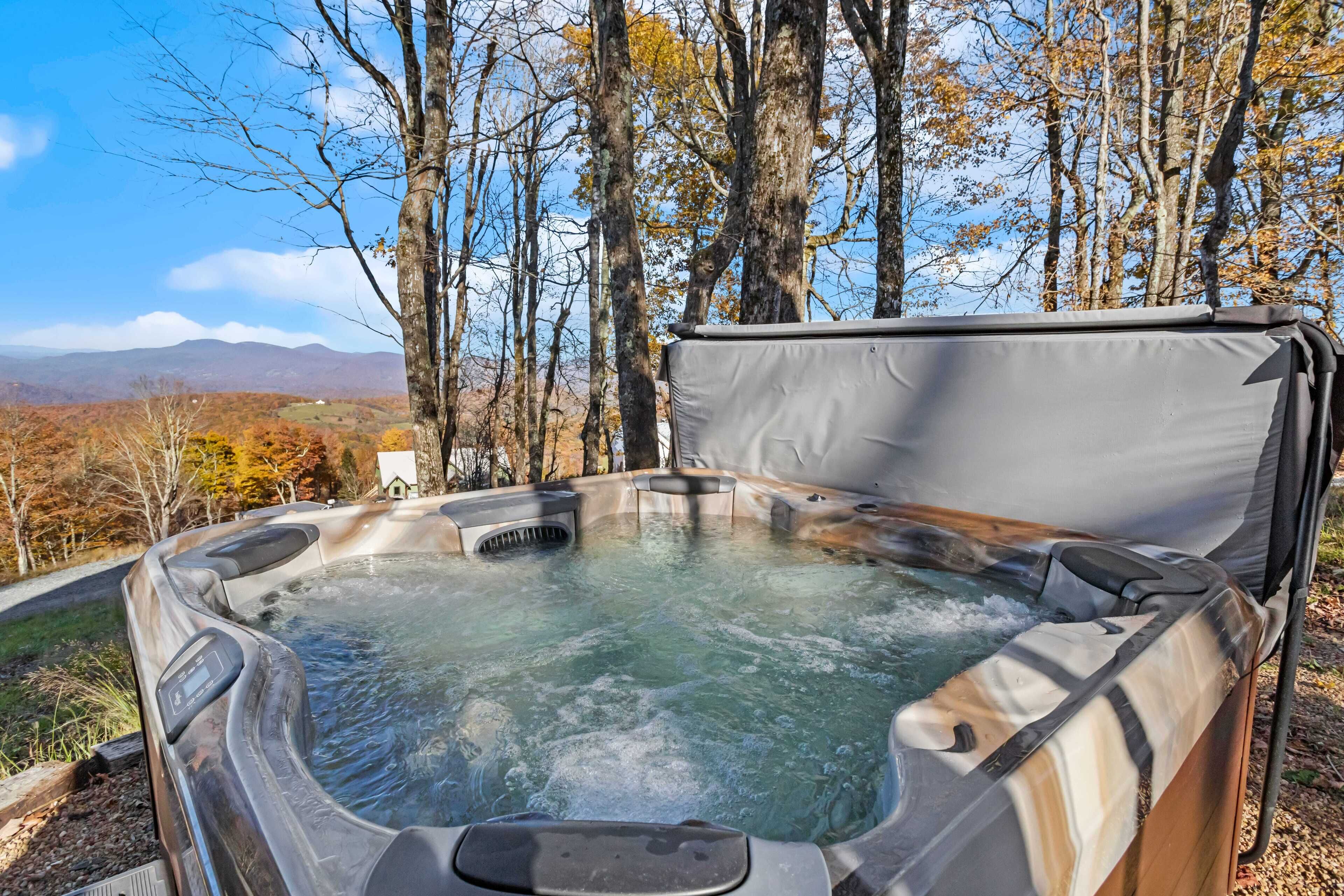 A hot tub with a view of a forest and mountains in the background.