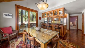 Un vaste espace dédié à la salle à manger, avec une table à plateau de verre, entourée de chaises en bois. On aperçoit, au fond, une grande armoire en bois dotée de portes en verre.