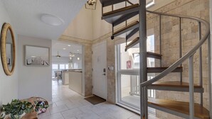 A modern interior with a spiral staircase, a wooden bench, and a large mirror. - 10 Pipers III – Beachfront Bliss with Ocean Views, Private Balcony & Grill Area (Indian Rocks Beach)