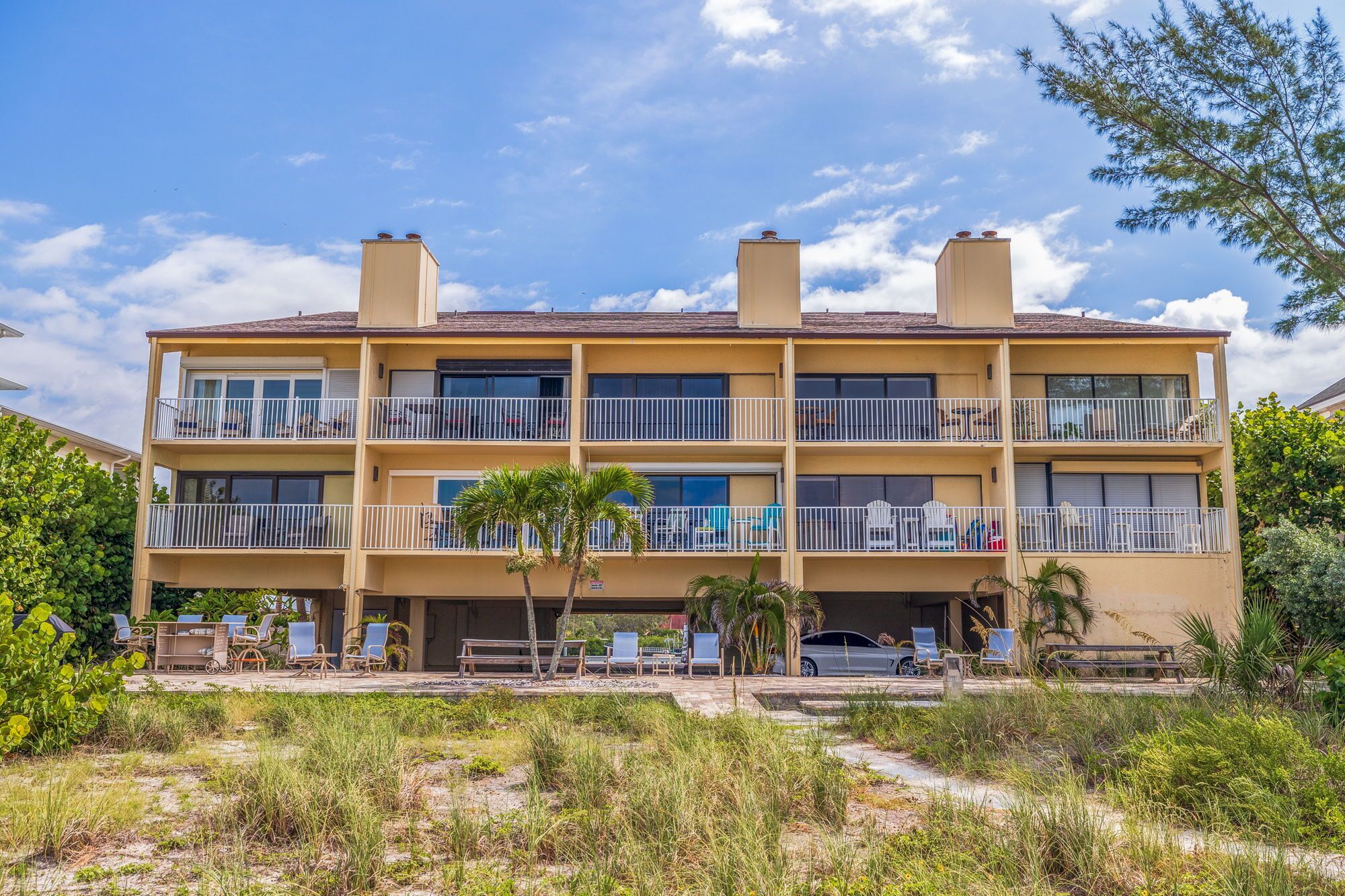 Un hotel de varios pisos con balcones, mobiliario exterior y una zona de piscina.