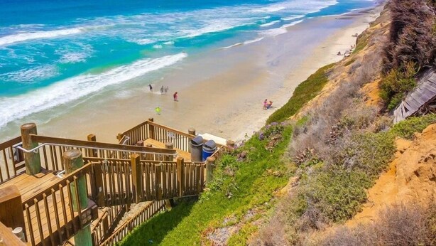 Une terrasse en bois donnant sur une plage avec vue sur l’océan.