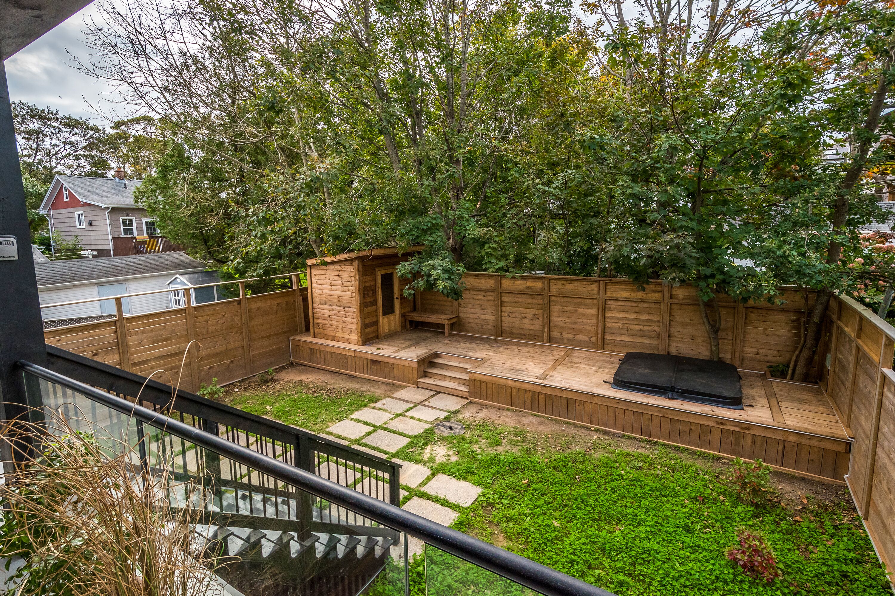 A backyard with a wooden deck, a small wooden structure, and a grassy area.