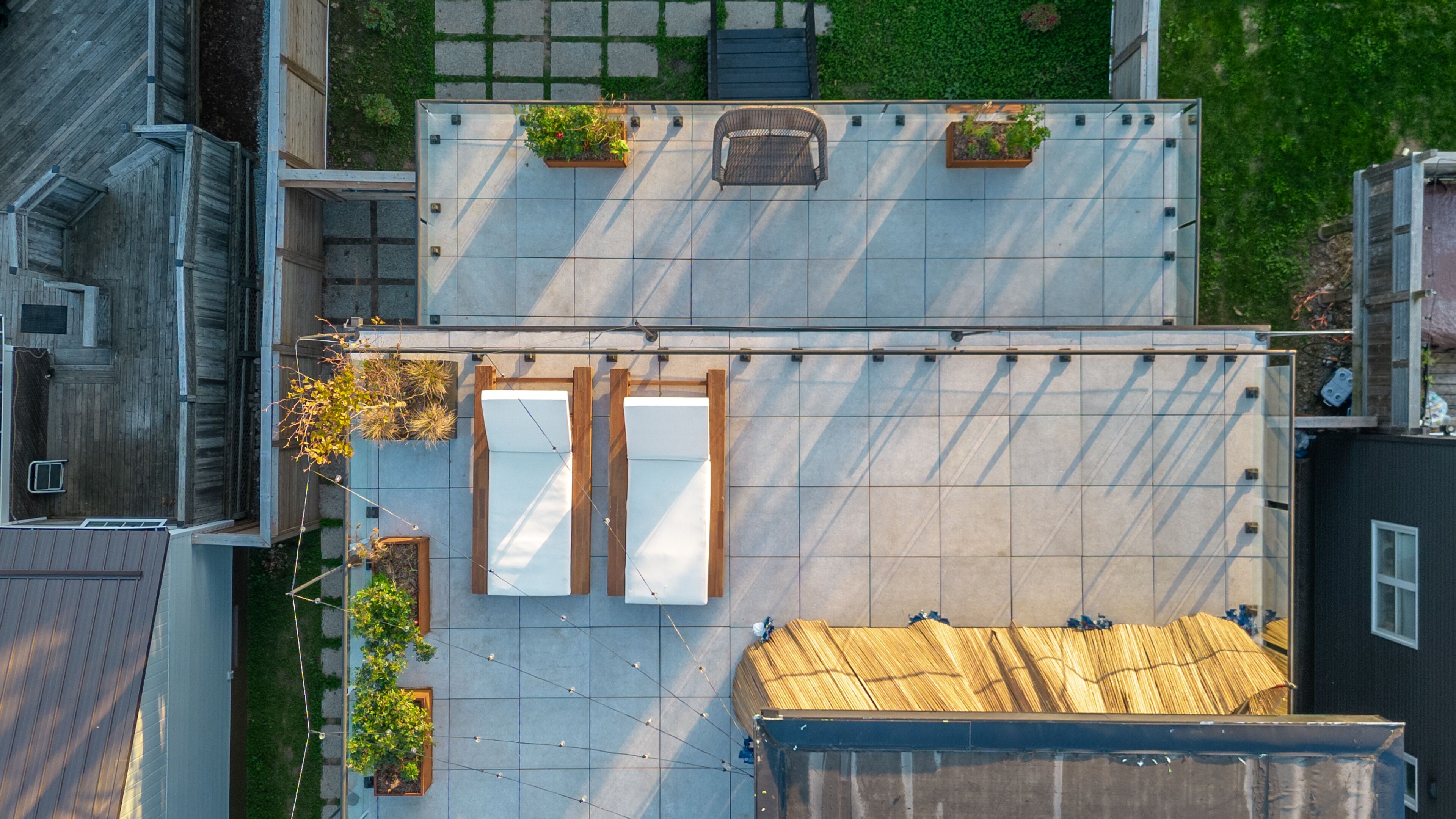 An aerial view of a rooftop with a large open space, two wooden doors, and potted plants.