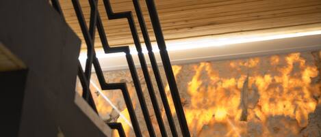 A staircase with a wooden handrail and a metal railing, leading to a room with a marble floor.