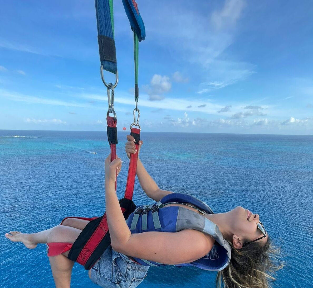 A person parasailing over a body of water with a clear sky in the background.
