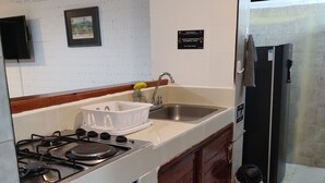 Une cuisine équipée d’une cuisinière à gaz, d’un évier et d’un réfrigérateur.
